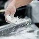 Person sprinkling flour across working surface